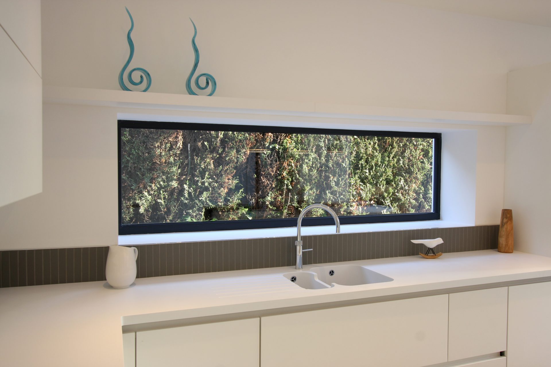 horizontal slime glass window above a sink area in white kitchen