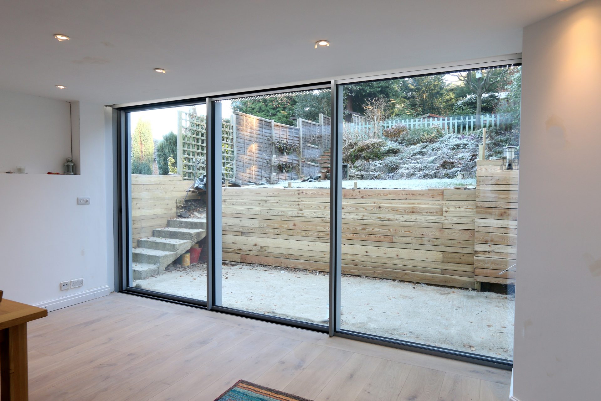 slim frame sliding doors leading onto an outdoor area featuring a small panelled wall