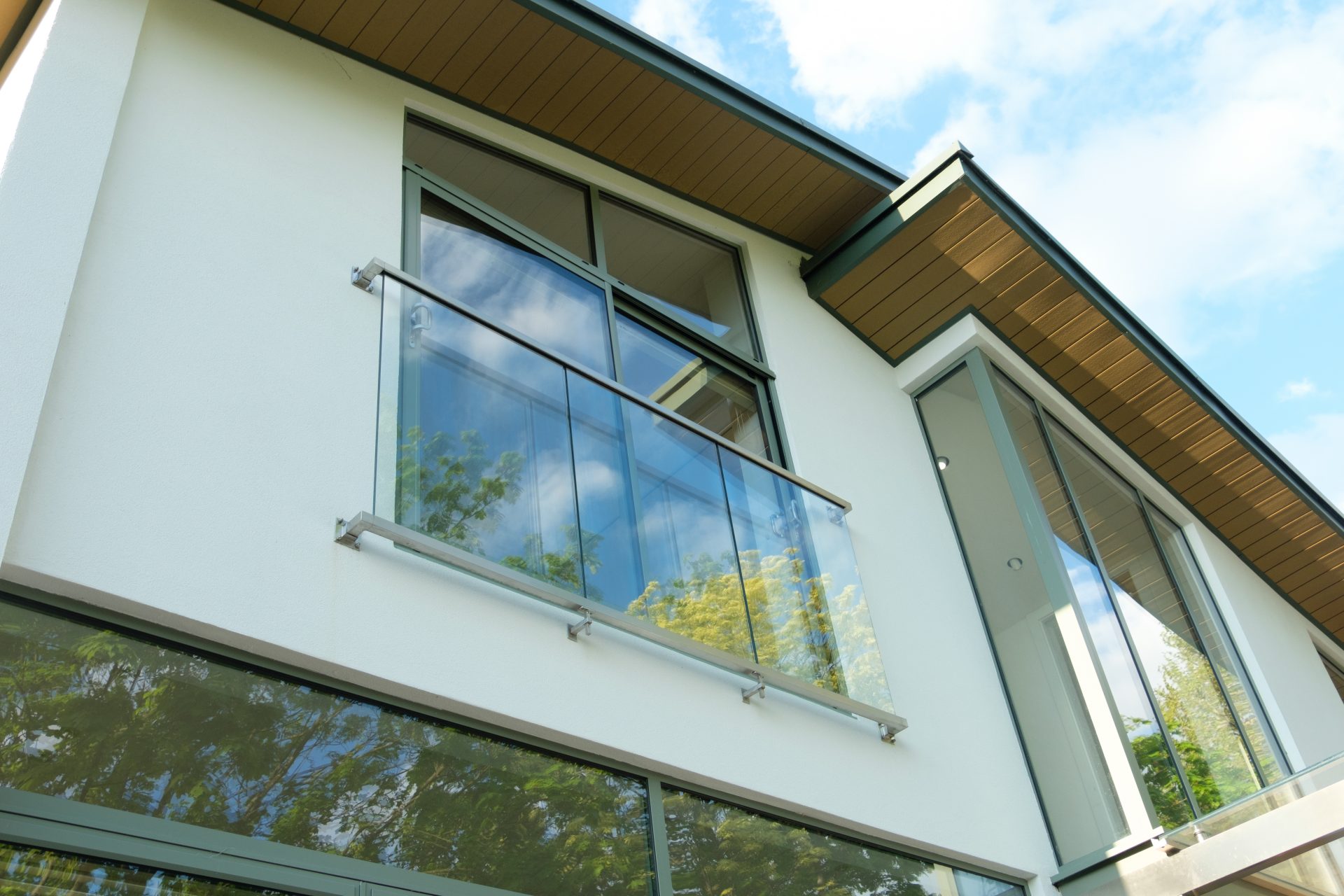 modern house exterior with large glass windows and a small glass balcony with metal railings.