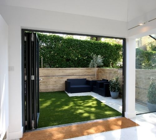 three pane schuco bifold door with traffic door and an outdoor seating area