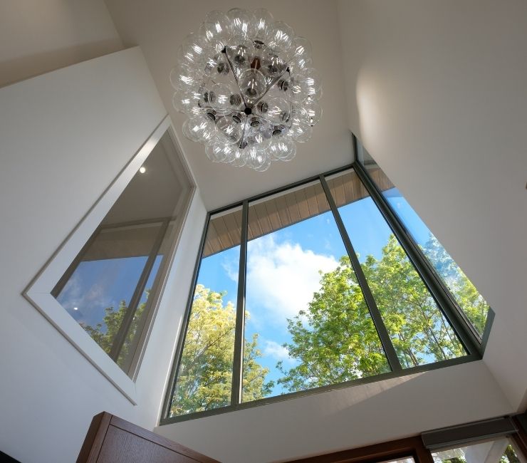 double height entrance way with fixed glazing and a unqiue light fixture to create a well lit inviting and modern home entrance